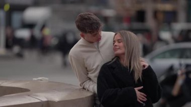 Genç bir çift Paris 'te bir şehir meydanında kucaklaşır kadın ve erkek açık havada romantik bir an paylaşır..