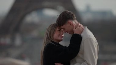 Paris 'teki Eyfel Kulesi' nin önünde genç bir çift kucaklaşıyor. Fransa 'daki el kamerası, aşıklar arasındaki romantik bağı yakalıyor..