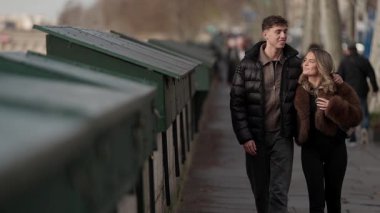 Bir çift Paris 'teki Seine Nehri boyunca yürür. Romantik yürüyüş nehir kıyısında gerçekleşir. Eiffel Kulesi uzaktan görülebilir..