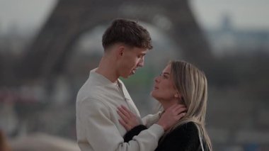 Paris 'te genç bir çift sevgiyle kucaklaşır. Arka planda Eyfel Kulesi görünür. Aşıklar birbirlerinin gözlerine bakar.