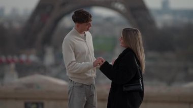 Romantik bir çift Paris 'te arka planda Eyfel Kulesi ile el ele tutuşuyor. Kadın ve erkek, seyahat ve turizm konseptini sergiliyor. Yavaş çekimde ya da el kamerasıyla çekiliyor..