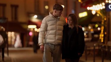 Romantik bir çift gece Paris 'te yürür Fransa' da genç bir adam ve kadın şehir caddesinde kol kola yürürler yumuşak, ılık bir ışık ve bokeh.