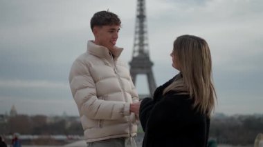 Bir çift Paris 'te arka planda Eyfel Kulesi ile el ele tutuşurken sahne, Paris şehrinin bulutlu zemininde birbirine aşık iki insan arasında geçen romantik bir anı yakalıyor..