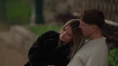 Genç bir çift Paris 'te sarılır kadın başını erkeğin omzuna koyar aşk ve bağlantının samimi bir anını yakalar sahne, açık havada huzurlu bir şekilde romantizm ve şefkat taşır..