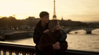 Romantik bir çift, Paris 'te arka planda Eyfel Kulesi' ne sarılır. Gün batımında Fransa 'da altın saat ışığı sıcak ve sevgi dolu bir atmosfer yaratır..