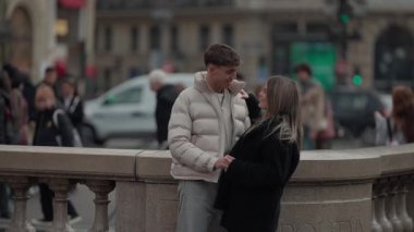 Romantik bir çift Paris 'te bir köprüde kucaklaşır arka planda şehir trafiği ve mimarisi bulanıklaşır..