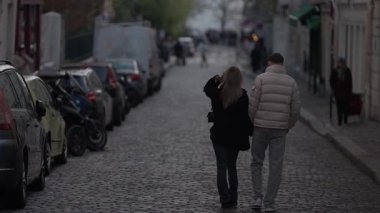Montmartre Paris 'te bir kaldırım taşı caddesinde bir çift yürür. Arka manzara, Avrupa' da bulutlu bir günde gezinen bir kadın ve bir erkeğin romantik bir yürüyüşü yakaladığını gösterir..