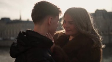 Paris 'te romantik bir çift, Fransa' da kadının erkeğin şefkatli binalarına dokunması arka planda görünür sahne altın saat ışığı altında sığ bir tarla derinliği ile yıkanır..