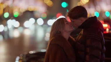 Genç bir çift gece Paris 'te kucaklaşır şehir ışıkları arka planda bir bokeh etkisi yaratır kadın ve erkek birbirlerine sevgiyle bakarken aşk ve beraberliğin özünü yakalar ışıklar şehrinde..