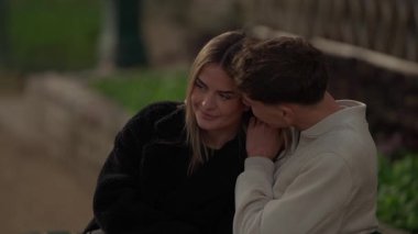 Paris 'te romantik bir çift, Fransa' da bir adam kadının kulağına fısıldıyor, samimi bir anda, yakın çekim, sığ bir alan derinliğinde, açık havada sevgi ve şefkat yakalıyor..