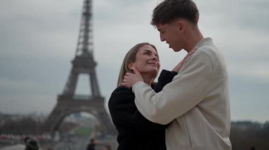 Genç bir çift Paris 'te Eyfel Kulesi' nin arkasında Fransa 'yı kucaklıyor. Aşıklar romantik bir ortamda birbirlerine eşlik ediyorlar..