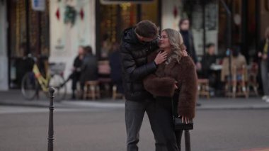 Romantik bir çift Paris 'te bir caddede kucaklaşır. Arka planda, bir ve diğer insanlar bir Avrupa şehrinde sevgi ve kentsel yaşam sahnesini yakalar..