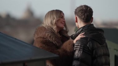 Romantik bir çift arka planda Paris siluetine sarılır kadın kürk ceket giyer ve erkek ceket giyer Fransa 'da yavaş çekim etkisiyle bir aşk ve sevgi anı yakalar..