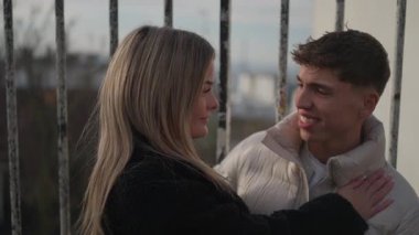 Paris 'te sevgi dolu bir çift romantik bir ışıkla sarılır şehir silueti metal bir çitin arkasında görünür sevgi ve beraberlik anları için güzel bir zemin oluşturur..