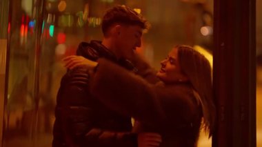 Genç bir çift gece Paris 'te sarılıyor. Sıcak ışıklandırma ve bokeh arka plan romantik bir atmosfer yaratıyor. Erkek ve kadın şefkatle el ele tutuşuyor..