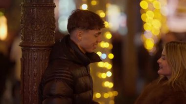 Genç bir çift Paris 'te bir sokak lambasının yanında konuşuyorlar. Fransa' da gece vakti sahne bokeh ışıklarıyla aydınlatılıyor. Şehirde romantik ve şenlikli bir ortam yaratıyor..