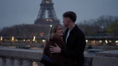 Romantik bir çift, Paris 'teki Eyfel Kulesi' nin yanında sarılır. Gün batımında Fransa 'da yavaş çekim, aşıkları Avrupa seyahatleri ve romantizm konseptinde birlikte vakit geçirirken yakalar..