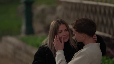 Paris 'te genç bir çift açık havada samimi bir anı paylaşıyor. Kız arkadaş, erkek arkadaşının burnuna şakayla dokunuyor. Sahne, sevgiyi ve birlikteliği doğal ışıkta yakalıyor..