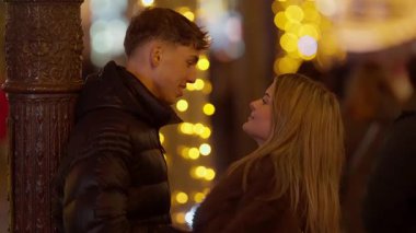 Genç bir çift gece Paris 'te bir caddede konuşurken adam arka planda bir sokak lambasına yaslanıyor Noel ışıkları görülebilir bir bokeh etkisi yaratıyor çift aşık görünüyor ve şehirde birlikte vakit geçiriyorlar..