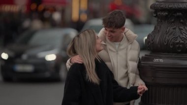 Paris 'te genç bir çift gün batımında bir sokak lambasına yaslanıp el ele tutuşurken görülüyor. Bu sahne, şehir ortamında bir aşk ve sevgi anı yakalıyor..