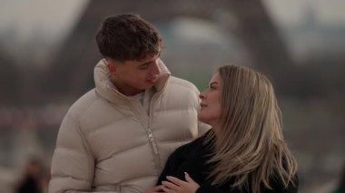 Genç bir çift Paris 'te Eiffel Kulesi' nin arkasında Fransa 'yı kucaklıyor ve konuşuyor..