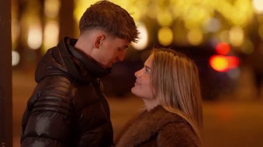 Paris 'te genç bir çift gece romantik bir anı paylaşıyor. Birbirlerine sevgi ve sevgiyle bakıyorlar. Arka planda sahte ışıklar ve sıcak ışıklandırmalı bir şehir sokak sahnesi var..