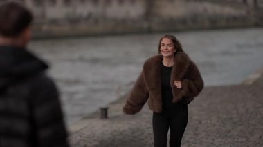 Paris 'teki Seine Nehri seti boyunca koşan mutlu sarışın bir kadının orta ölçekli bir resmi. Kadın kürk manto giyiyor ve nehir kenarında koşuyor. Klipsi şehir ortamını ve kadının neşeli hareketlerini yakalıyor..