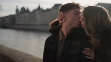 Romantik bir çift Paris 'te öpüşüyor Seine nehri ve arka planda şehir manzarası olan bir klip Avrupa' da bir aşk ve sevgi anı yakalıyor seyahat ve romantizm sergiliyor..