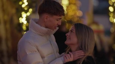 Genç bir çift gece Paris 'te romantik bir şekilde sarılır. Etrafı bokeh ışıklarıyla çevrilidir. Erkekler ve kadınlar tatil sezonunun tadını çıkarırlar..