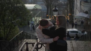 Genç bir çift Paris 'te Montmartre' ın merdivenlerinde kucaklaşır aşıklar aşk şehrinde sevgi dolu kucaklaşır el kamerasıyla romantik bir sahne yaratırlar..