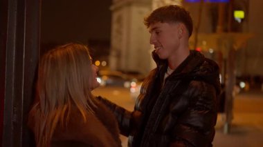 Genç bir çift gece Paris 'te el ele tutuşurken Arc de Triomphe arka planda görülüyor..