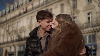 Genç bir çift Paris 'te romantik bir anda sarılıyor kadın ve erkek arka planda Parisli mimari ile kucaklaşıyor çekim el kamerasıyla ve ağır çekimde..