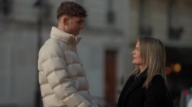 Paris 'te romantik bir çift, şehir ortamında birbirlerine sevgiyle bakar. Orta çekim, gerçek insanları doğal ışık ortamında yakalar. Sevgi ve bağlarını gösterir..