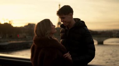 Romantik bir çift gün batımında Paris 'te Fransa' ya sarılır Eyfel Kulesi arka planda görünür altın saat ışıklandırması içerir ve çift arasında bir sevgi ve sevgi anı yakalar..