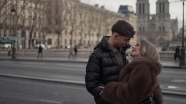 Romantik bir çift Paris 'te arka planda görünen Notre Dame Katedrali ile kucaklaşır..