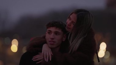 Paris 'te romantik bir çift alacakaranlıkta Fransa' da adamı kucaklıyor kadın şehir ışıklarının tadını çıkarırken adama sarılıyor şehir ortamında sevgi ve şefkat hissi uyandırıyor..