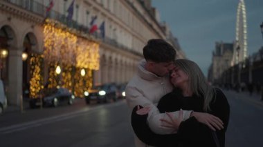 Paris 'te Rue de Rivoli' de romantik bir çift alacakaranlıkta birbirine sarılır. Arka planda dönme dolap görünür. Silah sesi, kucaklaşmayı ve şehrin ışıklarını hafifçe yakar..