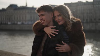 Romantik bir çift Paris 'te Fransa' da Seine nehri ve arka planda mimari ile kucaklaşıyor..