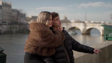 Genç ve romantik bir çift Paris 'i gezerken erkek, kürk giyen kadın onu kucaklarken bir şehir simgesini işaret ediyor. Sahne, bir nehrin arka planına ve Paris mimarisine karşı kurulmuş..