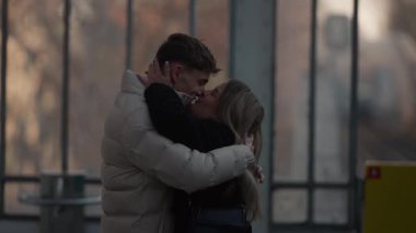Paris 'te genç bir çift kucaklaşır kadın ve erkek açık havada sevgiyle kucaklaşır şehirde romantik bir an paylaşırlar yumuşak doğal ışıklandırma sahneyi güzelleştirir.