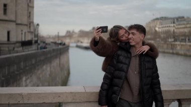 Genç bir çift Paris 'te, Fransa' da Seine nehri ve Notre Dame katedrali ile selfie çekiyor..