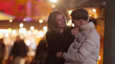 Romantik bir çift gece Paris 'te Fransa' da sarılır kadın bokeh ışıklarının ve açık hava festivalinin ortasında adama sevgiyle sarılır çift kış kıyafetleri giyip bir anlık şefkat ve sıcaklığın tadını çıkarır..