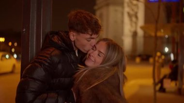 Romantik bir çift Paris 'te gece Fransa' da el ele tutuşuyor Arc de Triomphe arka planda görünüyor aşk şehrinde genç aşıklar kucaklaşıyor.
