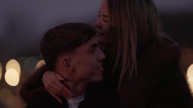 Genç bir çift gece Paris 'te kucaklaşırken görülüyor. Erkek ve kadın, arka planda Bokeh ışıkları ile samimi bir anı paylaşıyorlar. Şehrin ışıkları sahnenin romantik atmosferini aydınlatıyor..