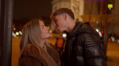 Paris 'te genç bir çift gece romantik bir anı paylaşıyor kadın şehirde kucaklaşan adama gülümsüyor ve Fransa' da aşk ilişkilerinin ve gece hayatının özünü yakalıyor..