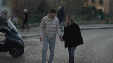 Genç bir çift, Paris 'te bir kaldırım taşı caddesinde el ele yürür. Romantik sahne, aşkın ve seyahatin özünü yakalar.