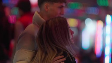 Genç bir çift, Paris sokaklarında yürür. El kamerasıyla çekilen fotoğraf, şehrin ışıklarından ve birbirlerinin arkadaşlığından keyif alırken romantik atmosferi yakalar..