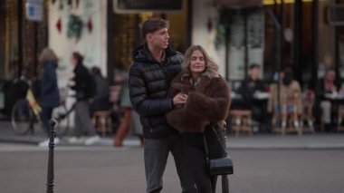 Romantik bir çift Paris caddesinde sarılır arka planda bulanık kafeler ve yayalar Paris 'in klasik bir sahnesini oluştururlar..