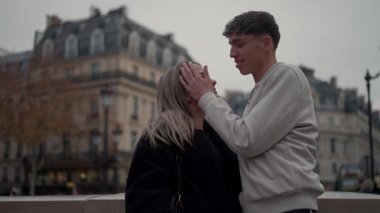 Paris 'te romantik bir çift arka planda Paris mimarisi ile kucaklaşır. Genç adam ve kadın bulutlu bir şehirde sevgi dolu bir anı paylaşırlar..