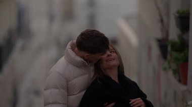 Paris 'te bir sokakta kucaklaşan romantik bir çift kabarık ceketli bir adam, şehir ortamında sevgi ve şefkat gösteren siyah ceketli bir kadına sarılıyor..